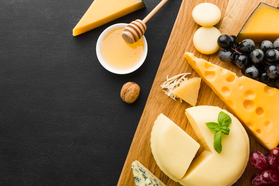 flat-lay-mix-of-gourmet-cheese-and-grapes-on-cutting-board-with-honey_23-2148376124.jpg